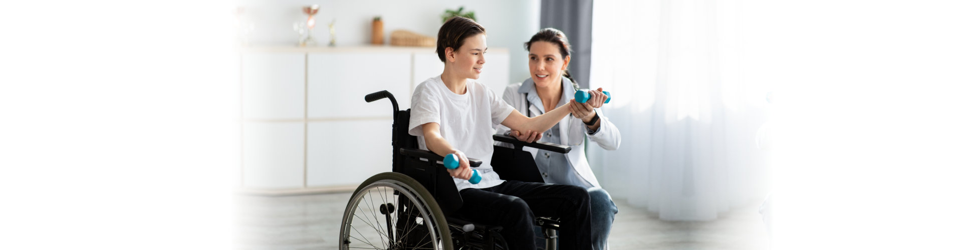 doctor helping teenage boy in wheelchair to do exercises